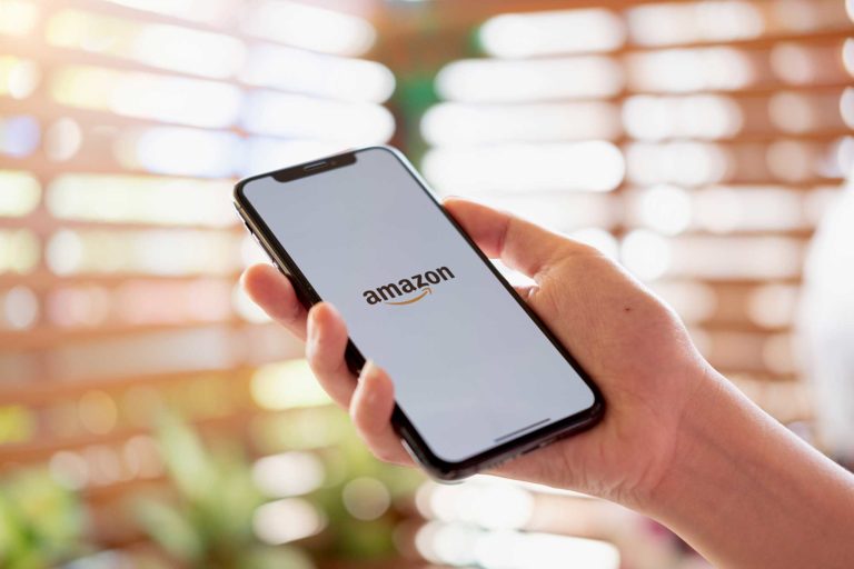 Hand met iPhone die Amazon logo toont